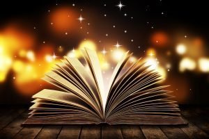 Open book on wooden vintage table with mystic magic bright light on background